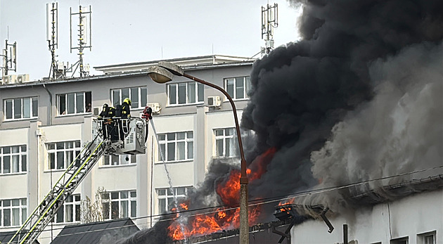 Na Žižkově hoří ubytovna, z budovy stoupá černý dým. Část střechy se propadla